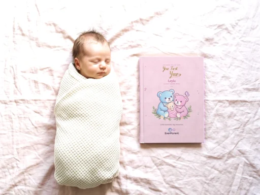 Sleeping newborn in a knitted blanket next to the pink baby book for Layla