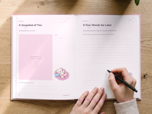 A hand writes memories into the pink baby book, a cup of tea beside it