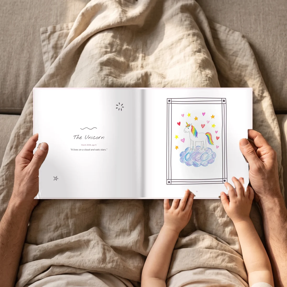 Open kids art book in pink on the sofa, held by an adult and a child